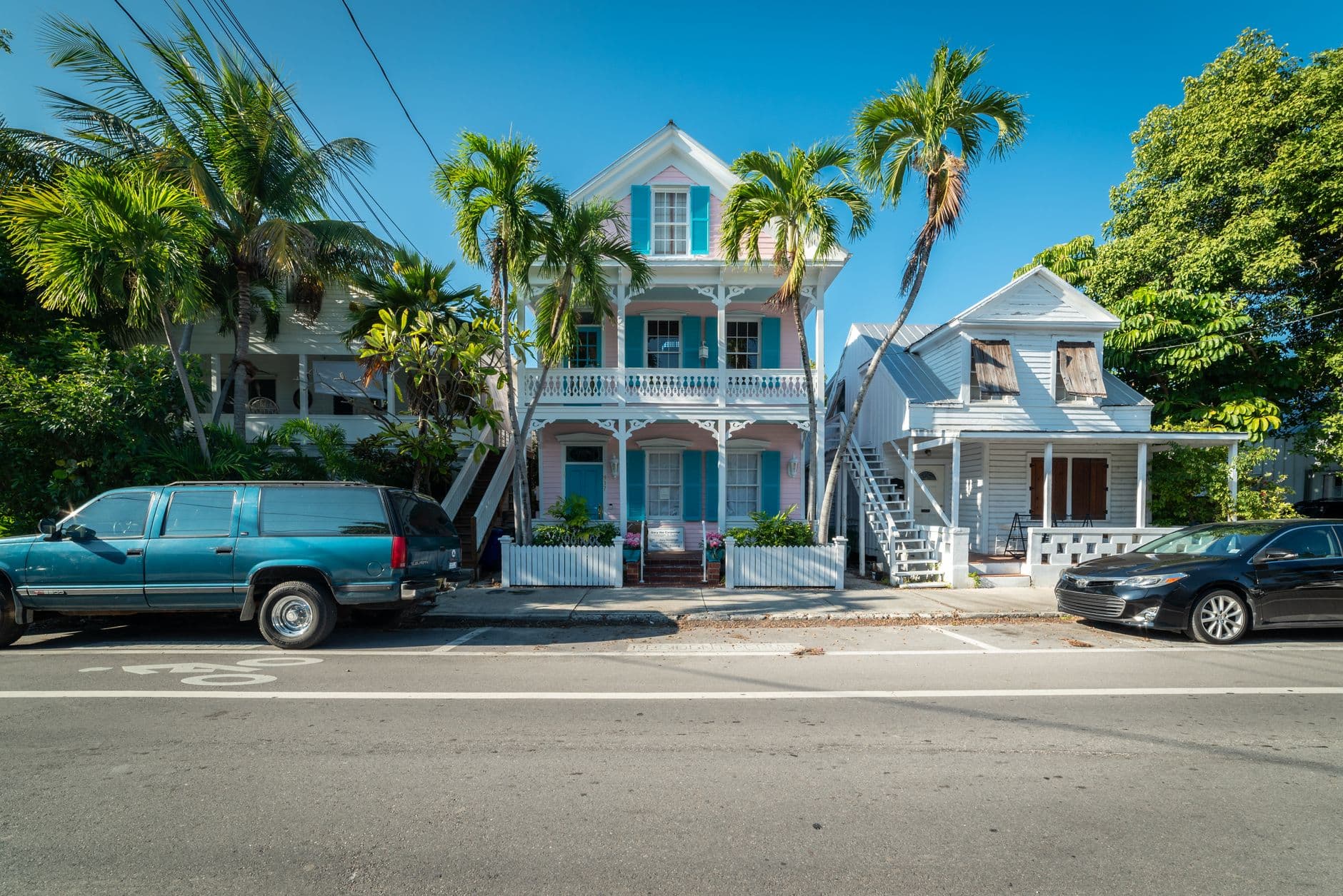 Colorful historic houses with palm trees along a sunny street in Key West, Florida.