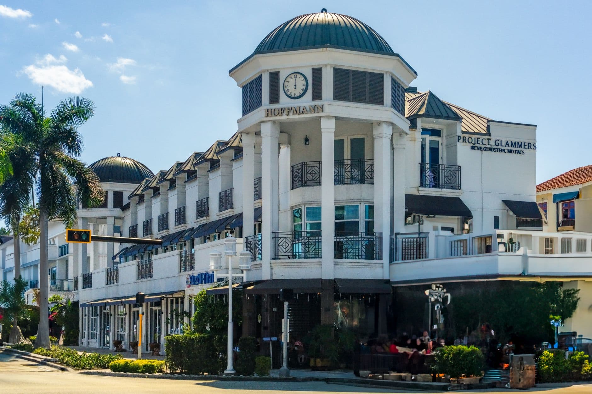 Elegant architecture at a shopping center in Naples, Florida with palm trees and clear skies.