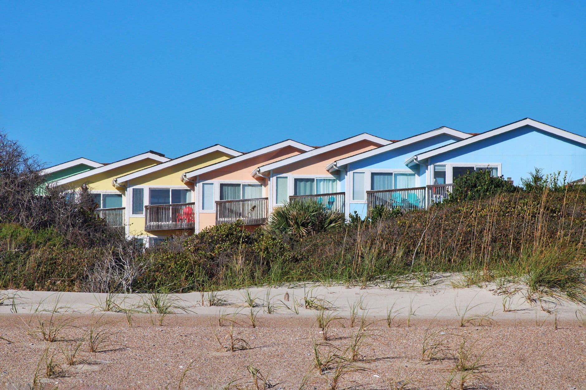 Colorful houses line a beachfront under a clear blue sky, showcasing vibrant architecture.
